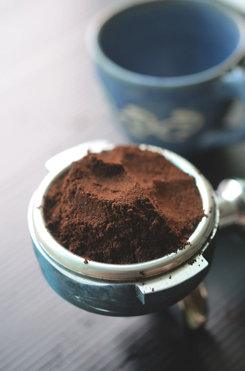 Freshly ground dark roast coffee powder in a metal espresso portafilter.